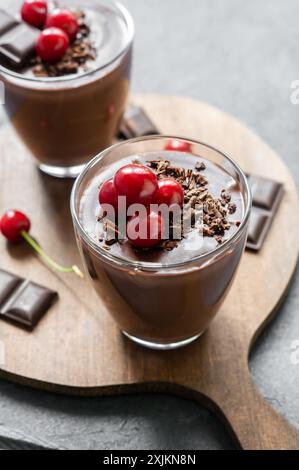 Pudding au chocolat et au cacao avec cerise aigre, mousse dans une tasse en verre sur une table rustique, supangle Banque D'Images