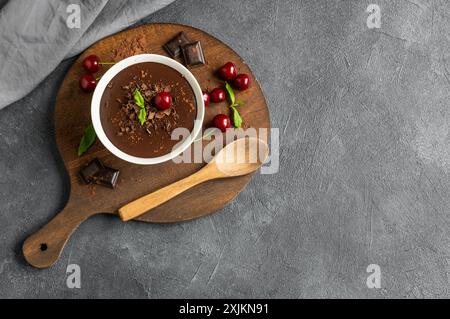 Pudding au chocolat et au cacao avec cerise aigre, mousse dans une tasse en verre sur une table rustique, supangle Banque D'Images