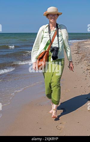 Femme âgée marchant pieds nus sur la plage, Darsser Ort, née a. Darss, Mecklembourg-Poméranie occidentale, Allemagne Banque D'Images