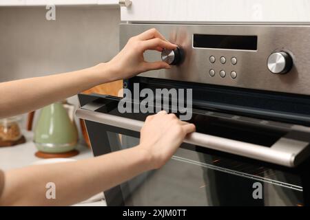 Femme utilisant un four électrique dans la cuisine, gros plan Banque D'Images