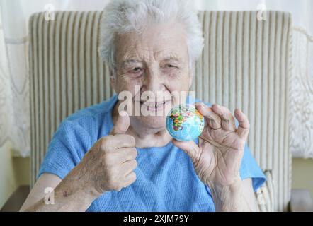 Une femme âgée tenant un globe Banque D'Images