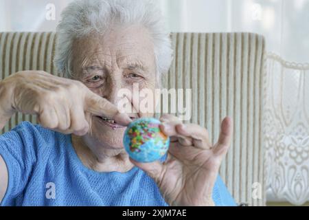 Une femme âgée pointant quelque part sur le globe Banque D'Images