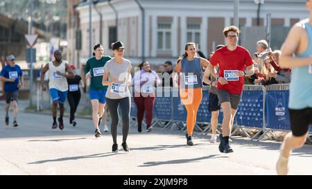 Groupe souriant de personnes participant à un marathon de la ville. Divers coureurs de course atteignant la ligne d'arrivée, célébrant leur victoire et atteignant leur objectif Banque D'Images