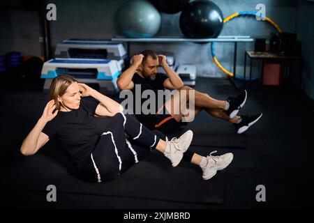 Deux athlètes d'âge moyen s'exerçant ensemble en fitness. Attrayant sportif et sportif faisant de l'exercice cardio assis-up pour rester fort Banque D'Images