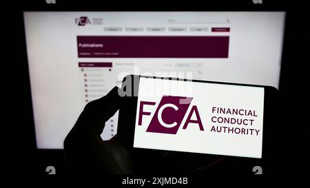 Stuttgart, Allemagne, 05 26 2022 : personne tenant un téléphone portable avec le logo de la British Financial Conduct Authority (FCA) sur l'écran devant la page Web. Mise au point Banque D'Images