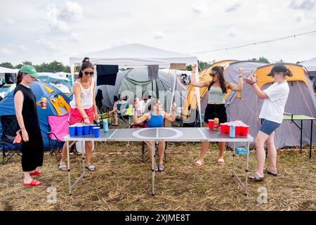 Nordholz, Allemagne. 19 juillet 2024. Les visiteurs du Festival Madlen (de gauche à droite), Elena, Sina, Sinja et Sarah de Hambourg jouent au jeu à boire Beer Pong sur le camping Deichbrand Festival. Le festival en plein air avec environ 60 000 visiteurs a lieu du 18 au 21 juillet. Crédit : Hauke-Christian Dittrich/dpa/Alamy Live News Banque D'Images