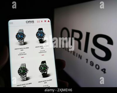 Stuttgart, Allemagne, 06-11-2022 : personne tenant un téléphone portable avec le site web de la société suisse de fabrication de montres Oris sa sur l'écran devant le logo. Mise au point Banque D'Images