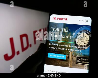 Stuttgart, Allemagne, 06-11-2022 : personne tenant un téléphone portable avec le site Web de la société américaine de recherche sur la consommation J.D. Power sur l'écran devant le logo. Concentrez-vous sur Banque D'Images