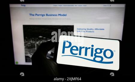 Stuttgart, Allemagne, 06-12-2022 : personne tenant un téléphone portable avec le logo du fabricant pharmaceutique Perrigo Company plc sur l'écran en face de la page Web. Banque D'Images