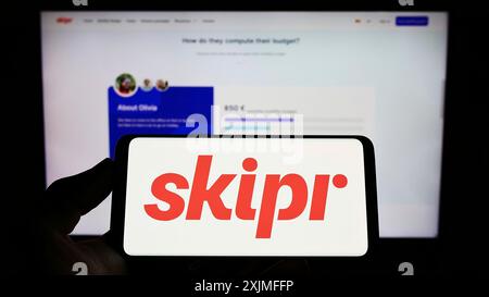 Stuttgart, Allemagne, 06-19-2022 : personne tenant un téléphone portable avec le logo de la société belge de mobilité Skipr sa sur l'écran devant la page web de l'entreprise. Mise au point Banque D'Images