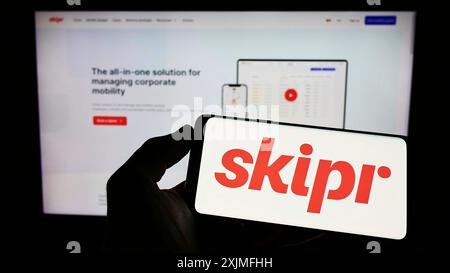 Stuttgart, Allemagne, 06-19-2022 : personne tenant un téléphone portable avec le logo de la société belge de mobilité Skipr sa sur l'écran devant la page web de l'entreprise. Banque D'Images