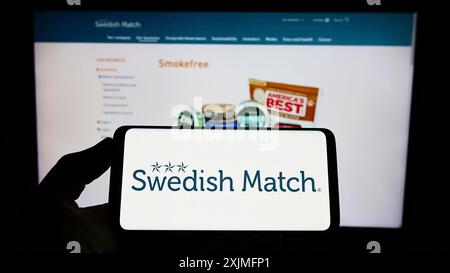 Stuttgart, Allemagne, 06-19-2022 : personne tenant un smartphone avec le logo de l'entreprise de tabac Swedish match AB sur l'écran devant le site Web. Concentrez-vous sur le téléphone Banque D'Images