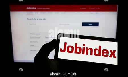 Stuttgart, Allemagne, 07-03-2022 : personne tenant un smartphone avec le logo de la société danoise de plate-forme de recrutement jobIndex COMME sur l'écran en face du site Web. Banque D'Images