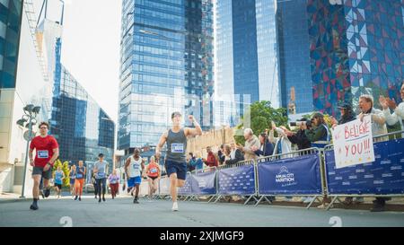 Portrait d'un homme d'âge moyen souriant qui court dans un marathon de ville, agitant devant le public de soutien. Amical Happy Male Runner célébrant le franchissement de la ligne d'arrivée dans une course Banque D'Images