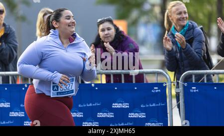 Portrait d'une coureuse féminine plus Size souriante traversant la ligne d'arrivée et démontrant sa volonté. Le public du marathon de la ville sympathique est favorable Banque D'Images