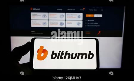 Stuttgart, Allemagne, 07-23-2022 : personne tenant un smartphone avec le logo de l'échange de crypto-monnaie sud-coréen Bithumb sur l'écran devant le site Web. Banque D'Images