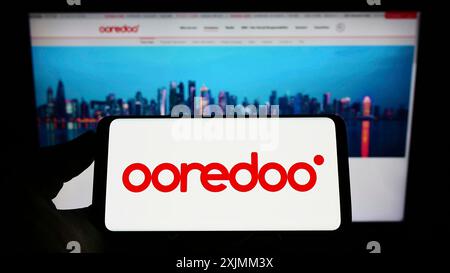 Stuttgart, Allemagne, 09-07-2022 : personne tenant un smartphone avec le logo de la société qatarienne de télécommunications Ooredoo QSC sur l'écran devant le site Web. Banque D'Images