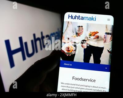 Stuttgart, Allemagne, 09-08-2022 : personne tenant un smartphone avec le site de la société finlandaise d'emballage Huhtamaki Oyj sur l'écran devant le logo. Mise au point Banque D'Images