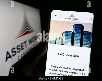 Stuttgart, Allemagne, 09-15-09 2022 : personne tenant un smartphone avec le site de la société immobilière thaïlandaise Asset World Corporation sur l'écran avec logo. Mise au point Banque D'Images