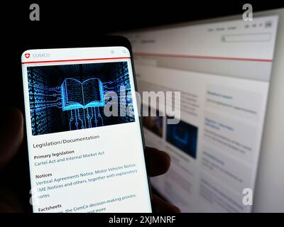 Stuttgart, Allemagne, 09-19-2022 : personne tenant un smartphone avec la page web du régulateur suisse Wettbewerbskommission (Weko) sur l'écran avec moniteur. Mise au point Banque D'Images