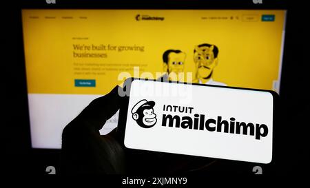 Stuttgart, Allemagne, 09-24-2022 : personne tenant un smartphone avec le logo de la plate-forme d'automatisation marketing Mailchimp sur l'écran devant le site Web. Mise au point Banque D'Images