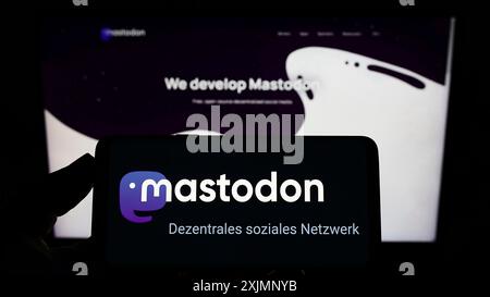 Stuttgart, Allemagne, 09-24-2022 : personne tenant un smartphone avec le logo du logiciel open source de médias sociaux Mastodon sur l'écran devant le site Web. Banque D'Images