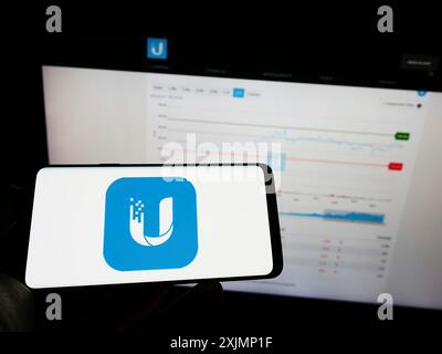 Stuttgart, Allemagne, 09-24-2022 : personne tenant un téléphone portable avec le logo de la société de technologie américaine Ubiquiti Inc. sur l'écran devant l'entreprise Banque D'Images