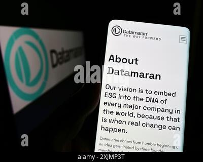 Stuttgart, Allemagne, 09-25-2022, personne tenant un téléphone portable avec la page Web de la société britannique de logiciels ESG Datamaran Ltd sur l'écran devant le logo. Banque D'Images