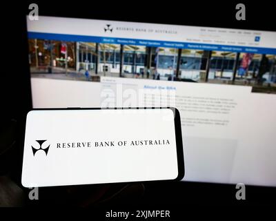 Stuttgart, Allemagne, 10-01-2022 : personne tenant un téléphone portable avec le logo de l'émetteur Reserve Bank of Australia (RBA) sur l'écran devant la page Web. Mise au point Banque D'Images