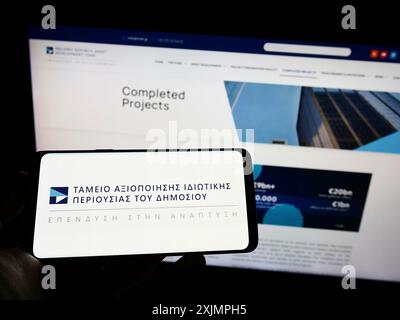 Stuttgart, Allemagne, 09-30-2022, personne tenant un téléphone portable avec le logo du Fonds de développement des actifs de la République hellénique (HRADF) sur l'écran en face de la page Web. Banque D'Images