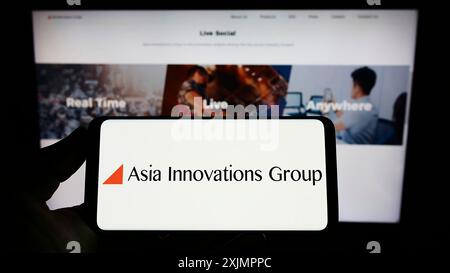 Stuttgart, Allemagne, 10-01-2022 : personne tenant un smartphone avec le logo de la société Internet Asia innovations Group (AIG) sur l'écran devant le site Web. Banque D'Images