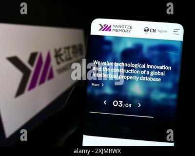 Stuttgart, Allemagne, 10-09-2022 : personne tenant un téléphone portable avec le site Web de la société Yangtze Memory technologies Corp. (YMTC) sur l'écran avec logo. Mise au point Banque D'Images