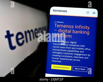 Stuttgart, Allemagne, 10-15-2022 : personne tenant un téléphone portable avec le site web de la société suisse de logiciels financiers Temenos sur l'écran devant le logo. Mise au point Banque D'Images