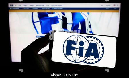 Stuttgart, Allemagne, 10-24-2022 : personne tenant un smartphone avec le logo de la Fédération internationale de l'automobile (FIA) sur l'écran devant le site Web. Mise au point Banque D'Images