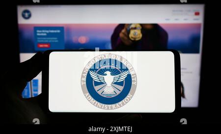 Stuttgart, Allemagne, 10-24-2022 : personne tenant un smartphone avec le sceau de la Transportation Security Administration (TSA) sur l'écran devant le site Web. Banque D'Images