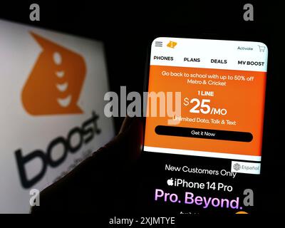 Stuttgart, Allemagne, 10-17-2022 : personne tenant un smartphone avec le site Web de la société de télécommunications américaine Boost Mobile sur l'écran devant le logo. Banque D'Images