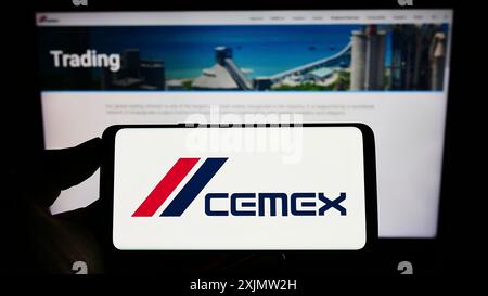 Stuttgart, Allemagne, 10-23-2022 : personne tenant un téléphone portable avec le logo de la société mexicaine de matériaux CEMEX SAB de CV sur l'écran devant l'entreprise Banque D'Images