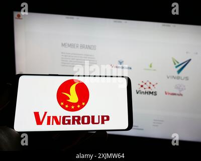 Stuttgart, Allemagne, 12-01-2022 : personne tenant un téléphone portable avec le logo du conglomérat vietnamien Vingroup JSC sur l'écran en face de la page Web de l'entreprise. Banque D'Images