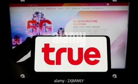 Stuttgart, Allemagne, 10-23-2022 : personne tenant un smartphone avec le logo de la société thaïlandaise de télécommunications True Corporation sur l'écran devant Banque D'Images