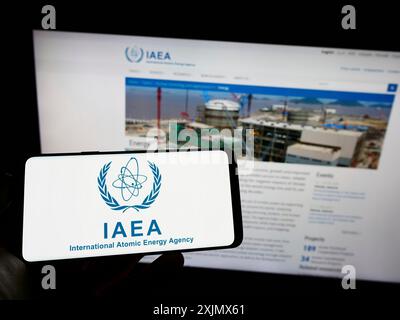 Stuttgart, Allemagne, 12-10-2022 : personne tenant un téléphone portable avec le logo de l'Agence internationale de l'énergie atomique (AIEA) sur l'écran devant la page Web. Mise au point Banque D'Images