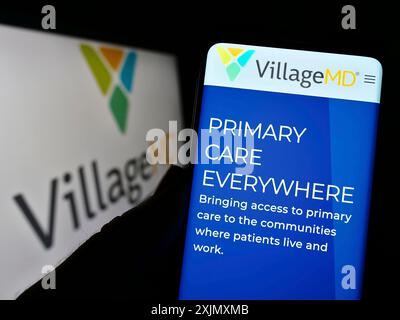 Stuttgart, Allemagne, 12-11-2022 : personne tenant un téléphone portable avec la page Web de la société américaine de soins de santé VillageMD sur l'écran devant le logo de l'entreprise. Mise au point Banque D'Images