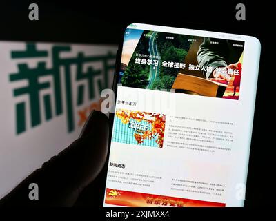 Stuttgart, Allemagne, 12-23-2022 : personne tenant un smartphone avec le site Web du New Oriental Education and Technology Group sur l'écran avec logo. Concentrez-vous sur Banque D'Images