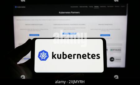 Stuttgart, Allemagne, 01-07-2023 : personne tenant un smartphone avec le logo du système d'orchestration de conteneur Kubernetes sur l'écran devant le site Web. Mise au point Banque D'Images