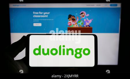 Stuttgart, Allemagne, 01-07-2023 : personne tenant un smartphone avec le logo de la société de technologie éducative Duolingo Inc. sur l'écran devant le site Web. Banque D'Images