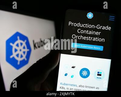 Stuttgart, Allemagne, 01-07-2023 : personne tenant un smartphone avec le site Web du système d'orchestration de conteneur Kubernetes sur l'écran devant le logo. Mise au point Banque D'Images