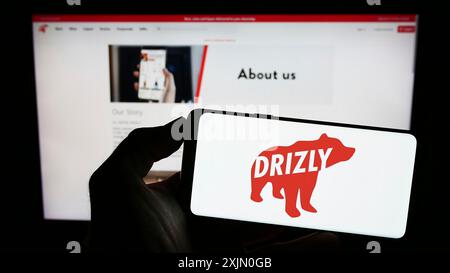 Stuttgart, Allemagne, 01-14-2023 : personne tenant un téléphone portable avec le logo de la société américaine de livraison d'alcool Drizly LLC sur l'écran en face de la page Web de l'entreprise. Banque D'Images