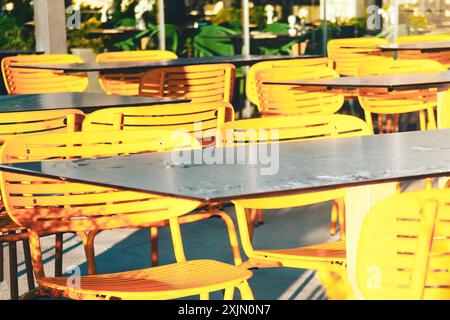 Les rangées de chaises jaunes sont alignées devant une table. Les chaises sont vides et la table est mouillée après la pluie. La scène dégage un atmo chaleureux et invitant Banque D'Images