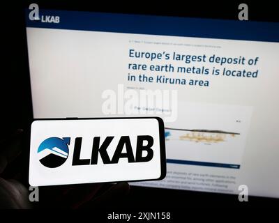 Stuttgart, Allemagne, 01-12-2023 : personne tenant un téléphone portable avec le logo de la société Luossavaara-Kiirunavaara AB (LKAB) sur l'écran devant l'entreprise Banque D'Images