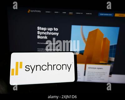 Stuttgart, Allemagne, 01-13-2023 : personne tenant un smartphone avec le logo de la société américaine de services financiers Synchrony Bank sur l'écran devant le site Web. Banque D'Images