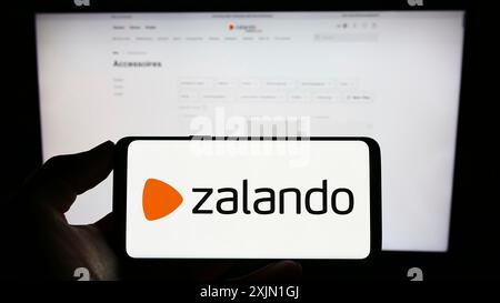 Stuttgart, Allemagne, 01-16-2023 : personne tenant un téléphone portable avec le logo de la société allemande de commerce électronique Zalando se sur l'écran en face de la page Web de l'entreprise. Banque D'Images